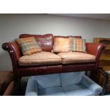 A burgundy leather and red fabric settee with scatter cushions