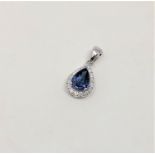 A 14ct white gold sapphire and diamond pendant, featuring centre pear cut blue sapphire (0.