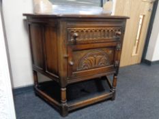 A carved oak side cabinet with a drawer and cabinet door