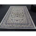 A contemporary machine made carpet on cream ground with floral borders