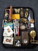 A tray of collectables inclduing pens, nut crackers, miniature brass toilet cistern,