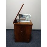 A twentieth century walnut sewing cabinet with Singer sewing machine and accessories