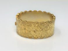 An ornate late Victorian gold plated hinged bangle with engraved decoration CONDITION