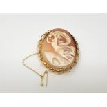 An ornate gold cameo brooch with gold safety chain