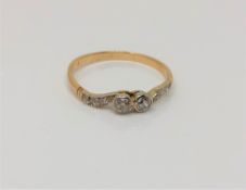 A gold two stone diamond ring with diamond set shoulders,