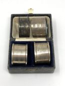 A boxed pair of silver napkin rings and two other loose examples