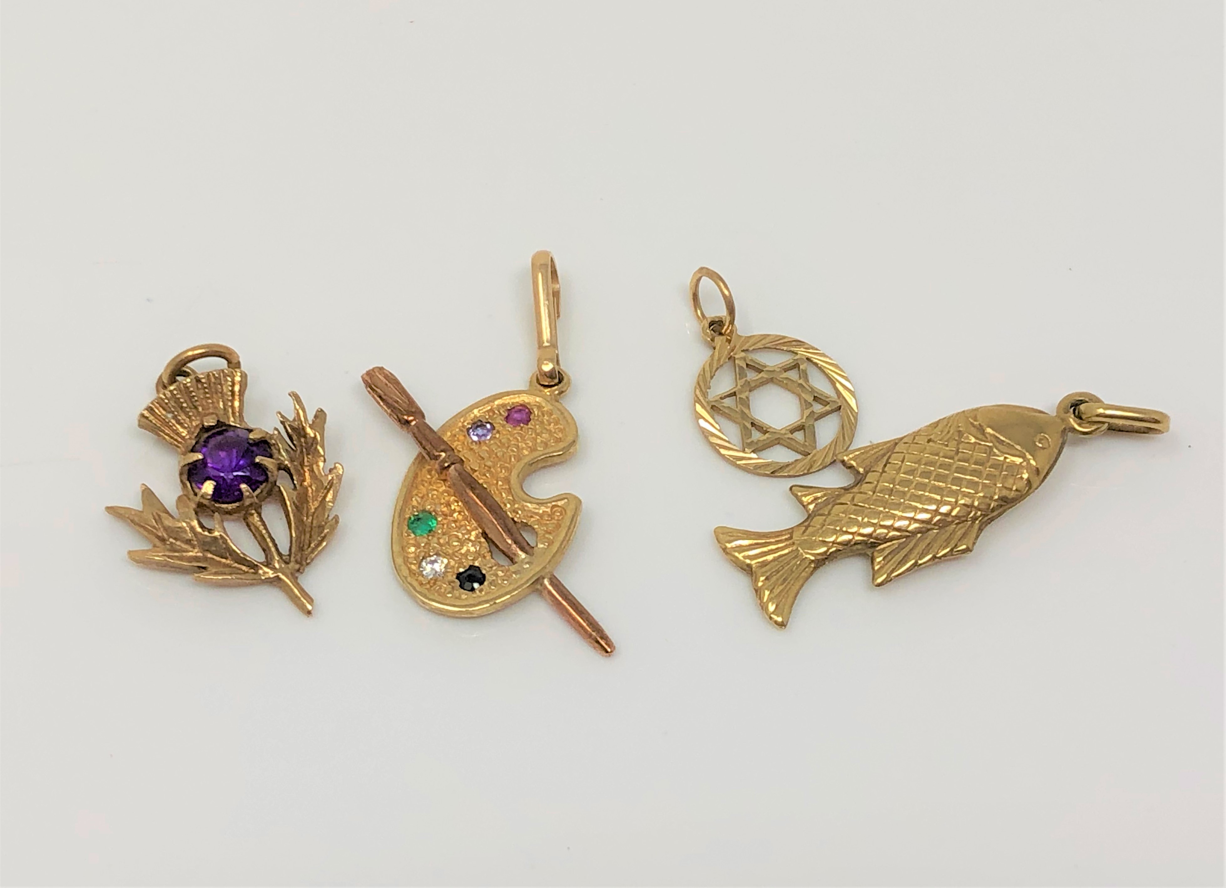 Four gold charms including an artist's palette set with emerald, amethyst,