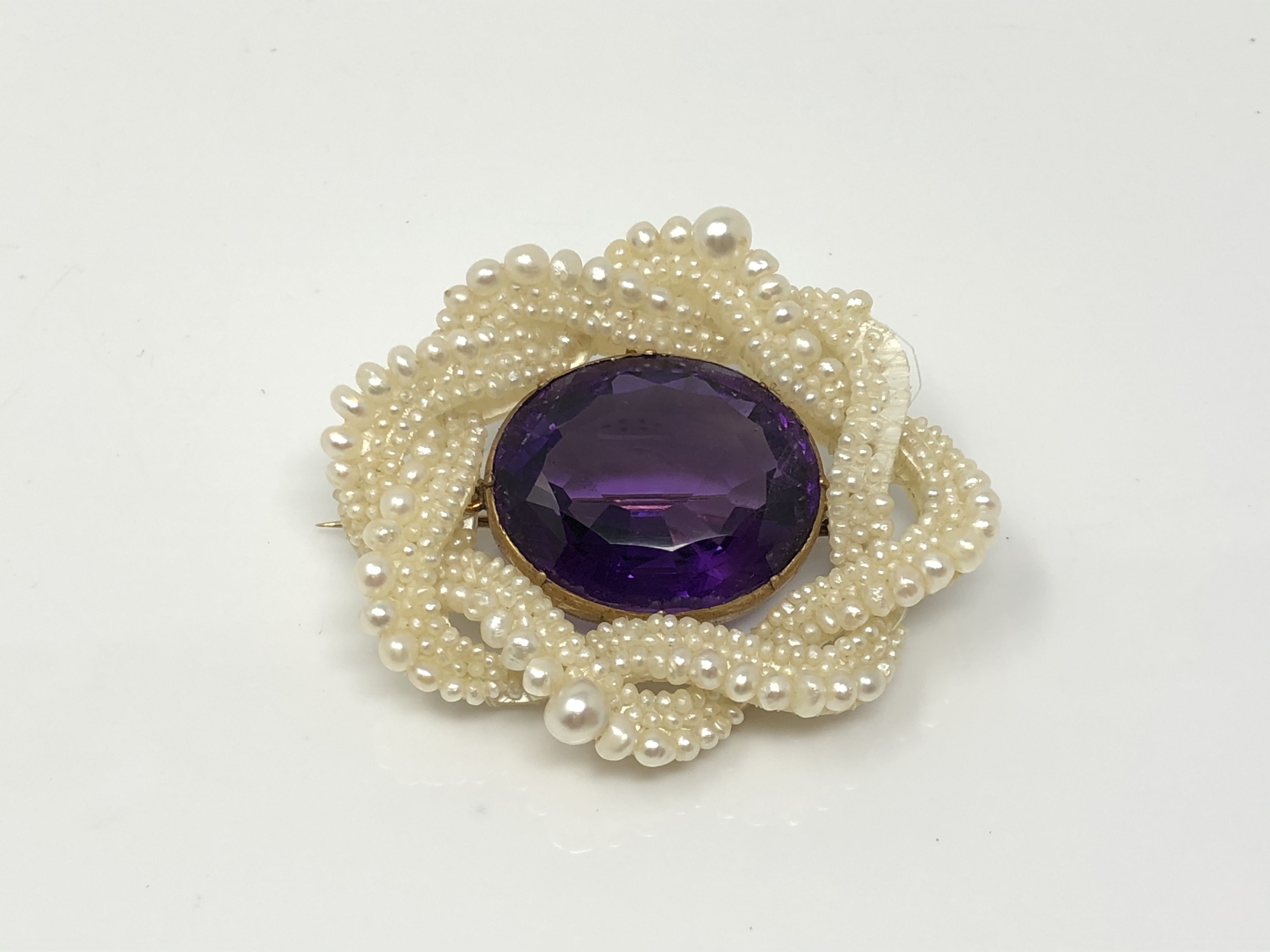 An antique amethyst and pearl brooch with gold fittings