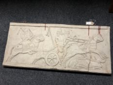A cast relief panel in metal frame depicting figures on chariot and horseback hunting, 95cm by 43cm.