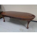 An oval Victorian mahogany wind out table with two leaves on claw and ball feet