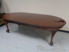 An oval Victorian mahogany wind out table with two leaves on claw and ball feet