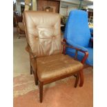 A wood framed high back armchair with a brown buttoned leather cushion