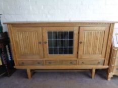A continental blond oak triple door sideboard fitted three drawers beneath on raised legs