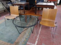 A pair of wooden tubular metal stacking chairs together with a circular coffee table on metal base