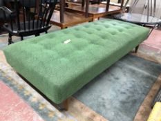 A mid 20th century day bed upholstered in a green buttoned fabric,