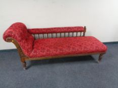 A late Victorian oak framed chaise longue in a red fabric