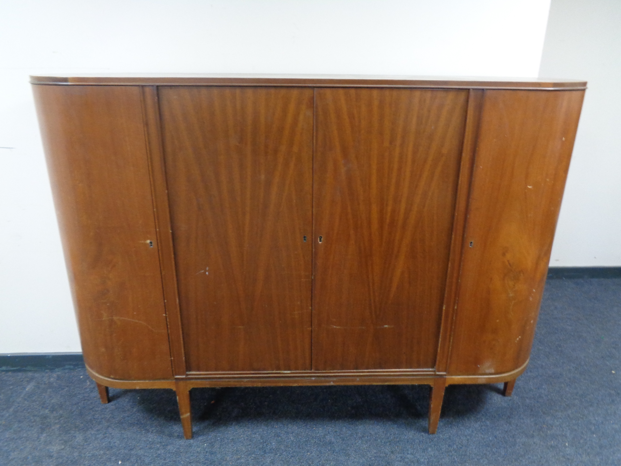 A mid 20th century teak four door sideboard on raised legs