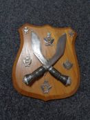 A pair of decorative Nepalese Gurkha knives with cap badges mounted on a shield