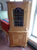 A 20th century blond oak corner display cabinet with leaded glass door fitted cupboard beneath