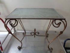 A wrought iron glass topped occasional table with fleur de lys understretcher