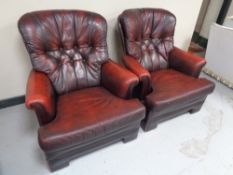A pair of red leather button back armchairs