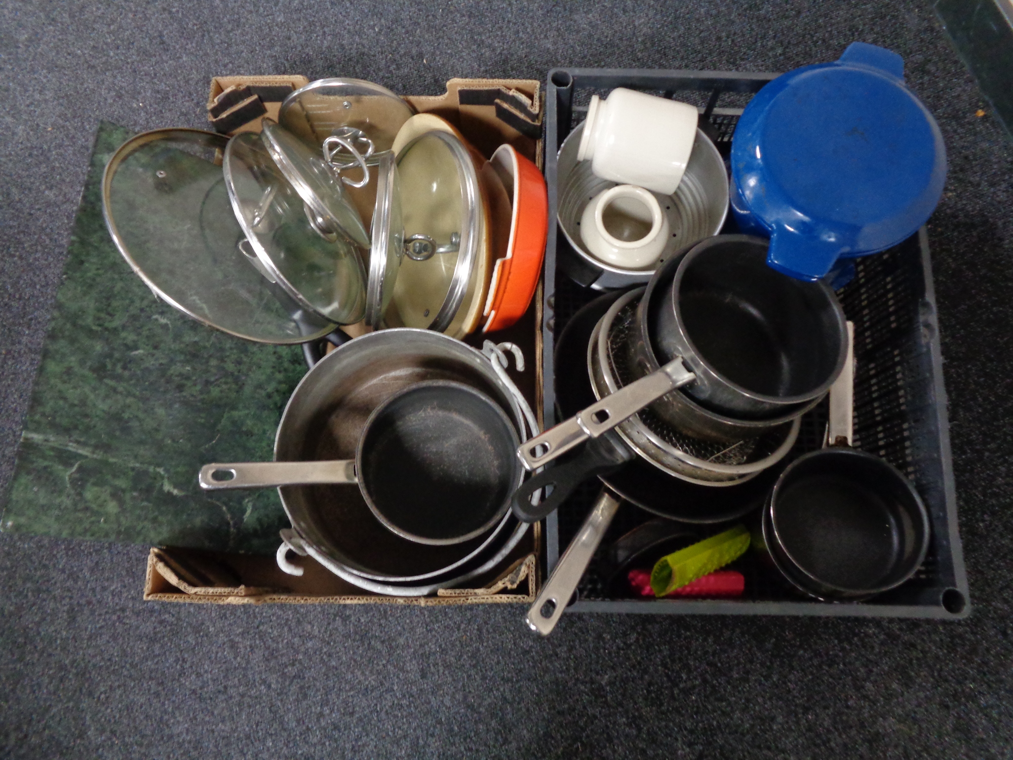 A box and a crate of kitchen ware including cast iron oven dishes, pans,