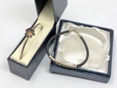 A silver and leather bangle and another all-silver bangle.