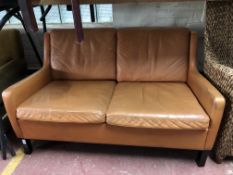 A 20th century Danish two seater settee upholstered in tan leather
