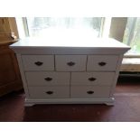 A contemporary white seven drawer chest with metal drop handles