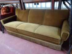 A 20th century continental three seater settee upholstered in olive dralon fabric