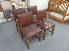 A set of four carved Edwardian oak dining chairs upholstered in brown studded leather