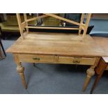 An antique pine writing table on reeded legs fitted two drawers