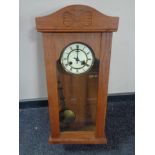 An early 20th century oak cased wall clock with brass and enamelled dial