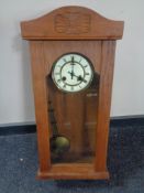 An early 20th century oak cased wall clock with brass and enamelled dial