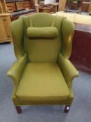 A 20th century wingback armchair upholstered in a olive green fabric