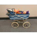 A mid 20th century doll's pram containing two plastic dolls