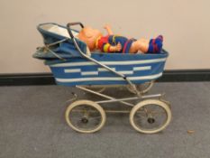 A mid 20th century doll's pram containing two plastic dolls