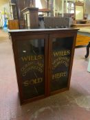 An Edwardian mahogany double door display cabinet bearing Wills Cigarettes advertising
