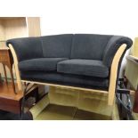 A late 20th century beech framed two seater settee upholstered in a black fabric