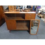 A mid 20th century teak sliding door bookcase and an un-framed mirror mounted on a teak board