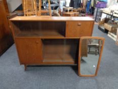 A mid 20th century teak sliding door bookcase and an un-framed mirror mounted on a teak board