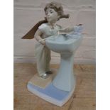 A Lladro figure of a girl stood at a sink
