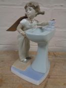 A Lladro figure of a girl stood at a sink