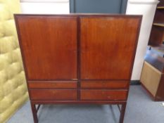 A stained beech double door cabinet fitted four drawers beneath, on raised legs, height 140 cm,