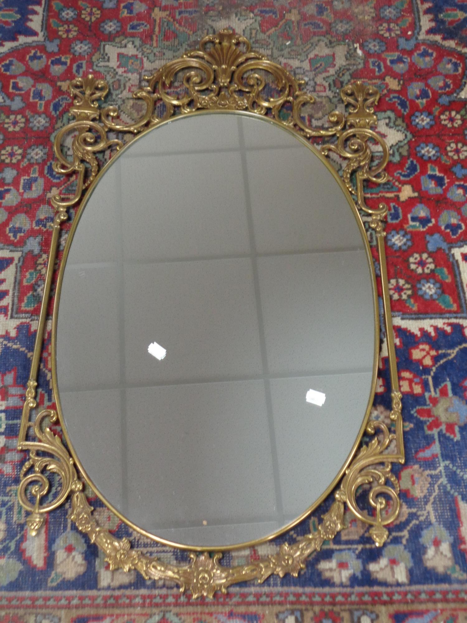 A decorative brass framed oval wall mirror 52 cm x 93.5 cm.