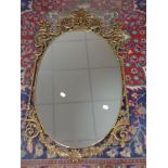 A decorative brass framed oval wall mirror 52 cm x 93.5 cm.