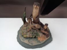 A Border Fine Arts figure of an otter family on slate stand