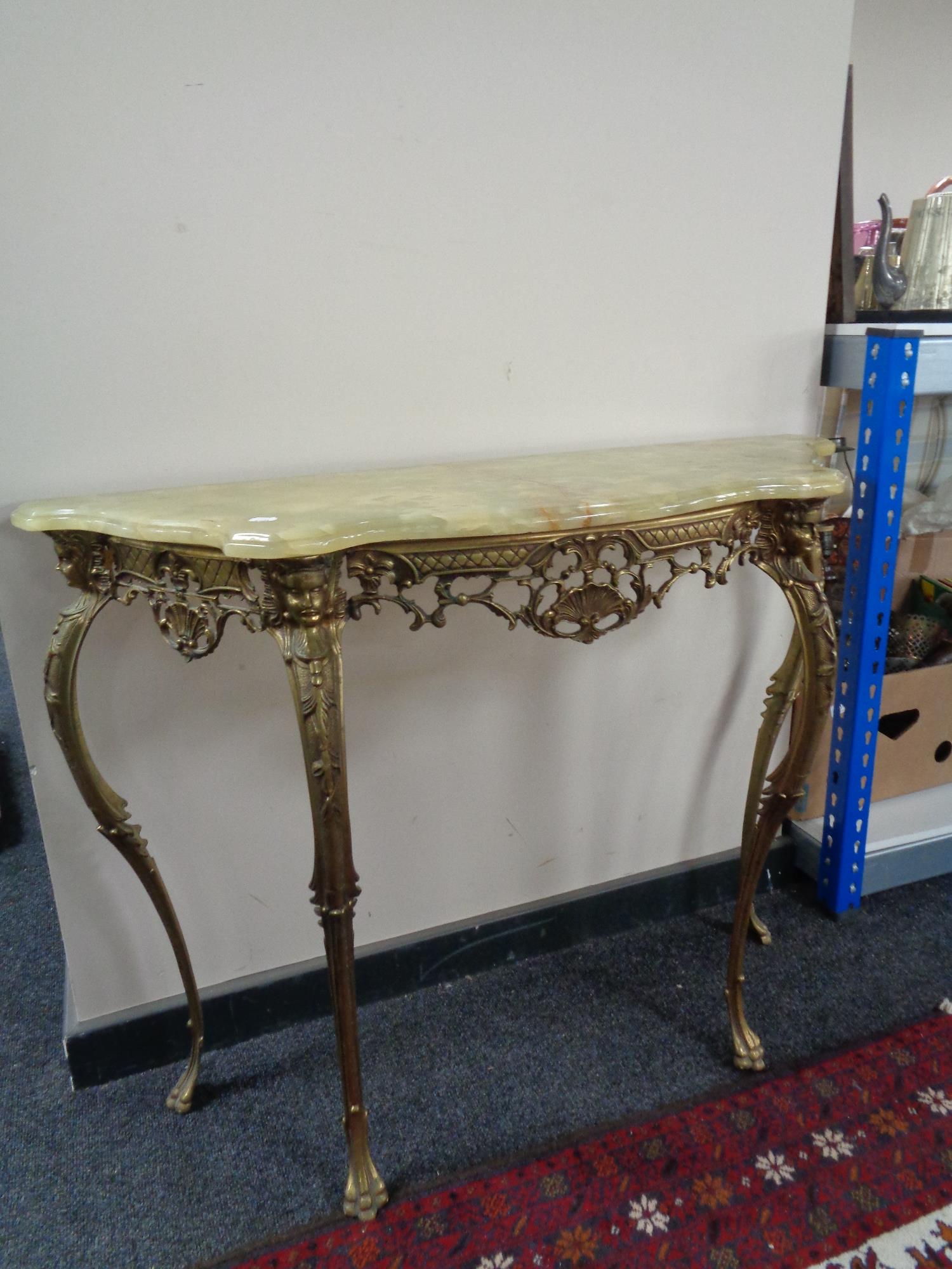 A shaped ornate onyx console table on brass legs, height 78 cm, depth 35 cm, width 103 cm.