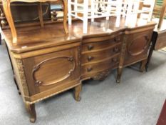 An antique mahogany serpentine fronted rail back sideboard fitted cupboards and drawers