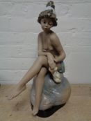 A large Spanish (Lladro?) figure of a nude female seated on rock on wooden stand, height 47 cm.